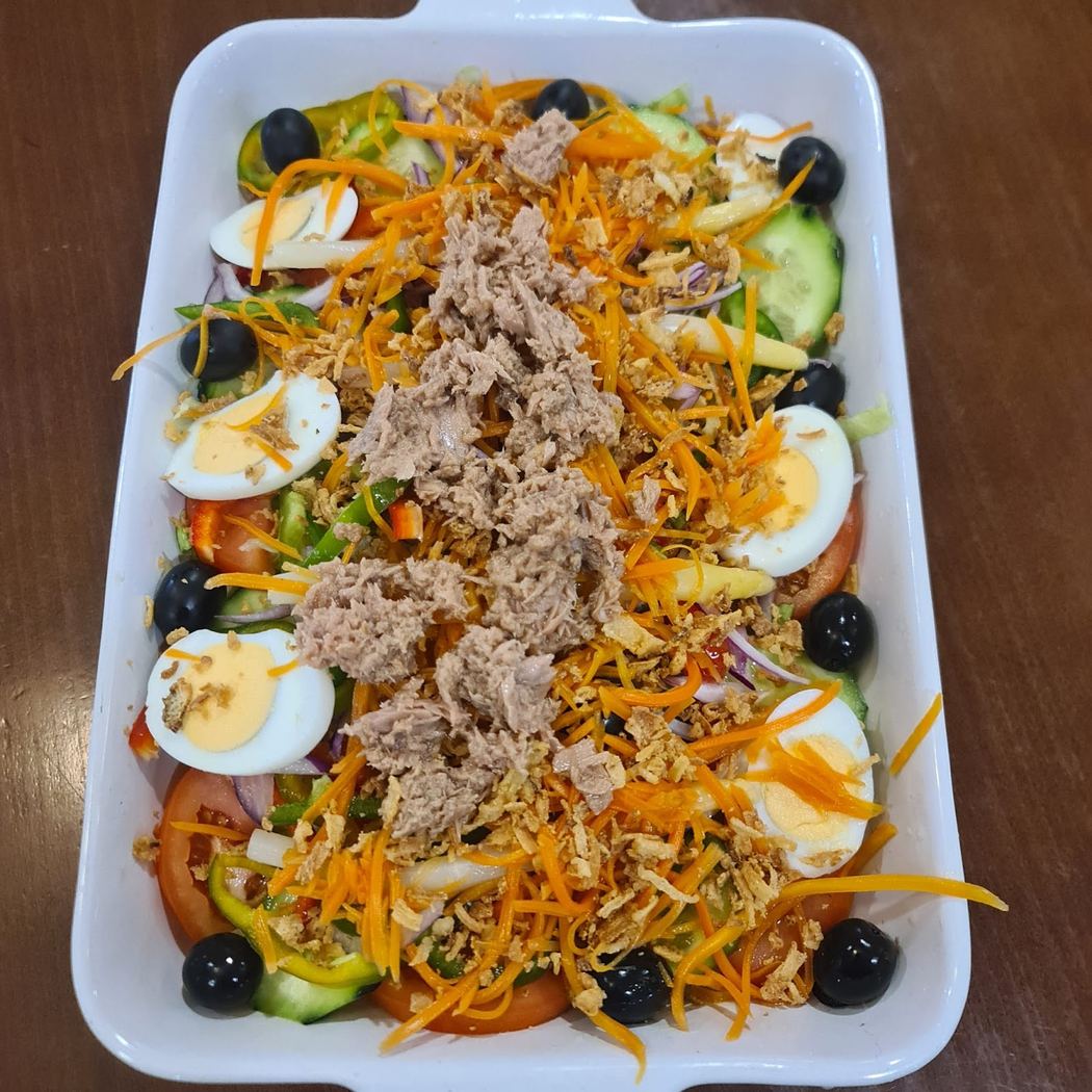 Ensalada mixta fresca con atún, huevo duro y verduras, aliñada con aceite de oliva y vinagre.
