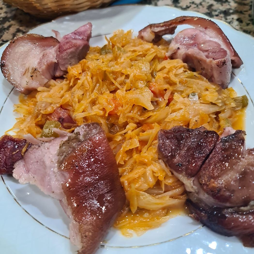 Guiso tradicional de repollo con manitas de cerdo, cocinado a fuego lento.